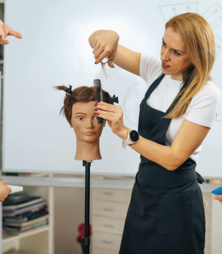 professional-hairdresser-teaching-adult-students-how-use-hairdressing-scissors-during-course